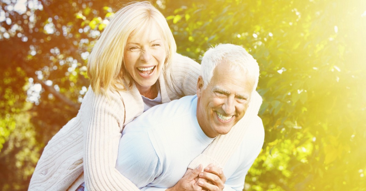 woman on man's back smiling and laughing because they trusted income for life